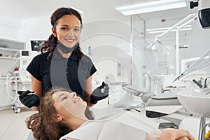 Front view of female dentist posing while curing teeth