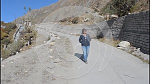 Front view of female woman hiker traveler tourist girl walking alone on mountain road in the summer while hiking enjoying nature.