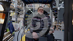 Front view forklift operator driving in large industrial warehouse indoors. Concentrated confident professional