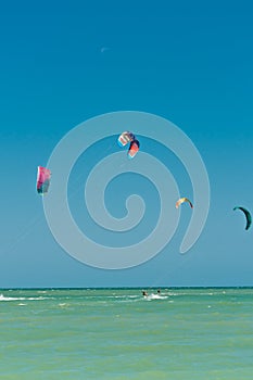 Front view of four, colorful canopy and kiteboarders