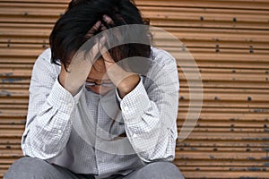 Front view of frustrated stressed young Asian business man with hands touching head and feeling disappointed or exhausted with job