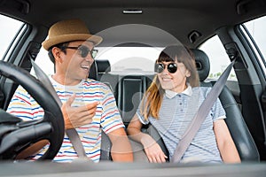 Front view of Funny moment couple asian man and woman sitting in car. Enjoying travel concept.