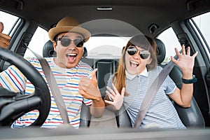 Front view of Funny moment couple asian man and woman sitting in car. Enjoying travel concept.