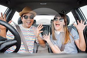 Front view of Funny moment couple asian man and woman sitting in car. Enjoying travel concept.