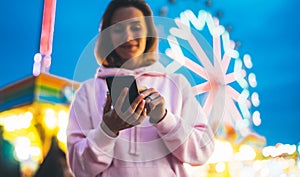 Front view girl pointing finger on screen smartphone on defocus background bokeh light in evening street attraction, woman using