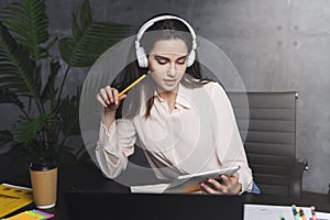 Front view. Girl sits in cafe at table in front of open laptop computer. Woman works on computer, checks email. Freelancer works