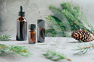 Front view of glass bottles of pine essential oil with fresh fir tree branch