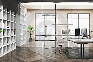 Front view on glass door in spacious office with modern computers on white table, big office cabinets, city view and parquet floor
