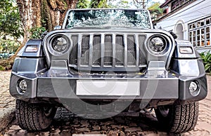 Front view of a gray classic 4x4 car parked in a backyard