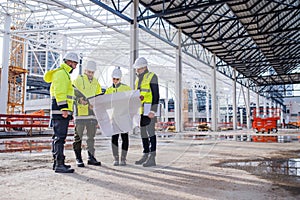 Group of engineers with blueprints standing on construction site. photo