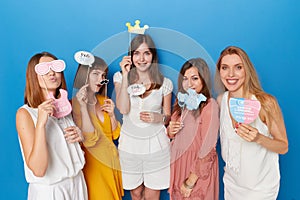 Front view of a group of joyful women to have gender reveals envent, isolated blue background. Copy space.