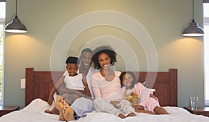 Happy African American family relaxing on bed and looking at camera