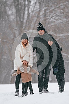 Front view. Happy family is outdoors, enjoying snow time at winter together