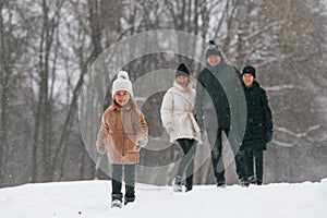 Front view. Happy family is outdoors, enjoying snow time at winter together