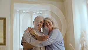 Front view of happy senior couple hugging and looking at camera