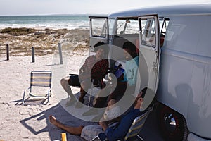 Happy young men relaxing near camper van at beach in the sunshine