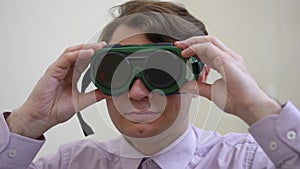 Front view headshot of confident man looking at camera putting on glasses for color blindness test. Caucasian male