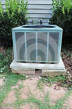 Front view of a heat pump showing unstable base propped up with blocks