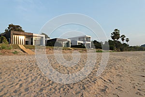Front view of house on the beach and a setting sun,