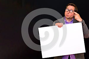 Front view image of caucasian Business man thinks something holding a blank banner isolated on black background