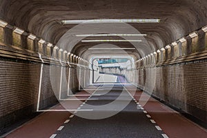 Front view of interior of an empty vehicular tunnel with cycle lanes with a curve in background