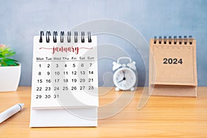Front view of January desk calendar for 2024 year and alarm clock with pen