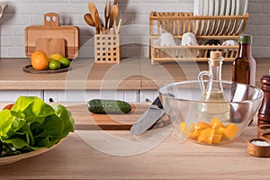 Front view of the kitchen table with salad ingredients. the background of a modern kitchen with household utensils on the