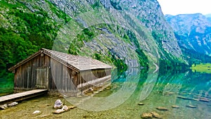 front view of lakeside cabin or traditional wooden boat house in Obersee on the left with a peaceful and clear lake on a