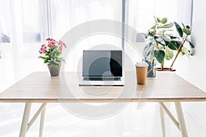 front view of laptop with blank screen, coffee cup, flowers and stationery