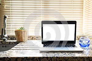 Front view of laptop with white screen in a kitchen with soft and warm light