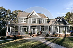 Front view of a large two story blue gray house with wood and vinyl siding