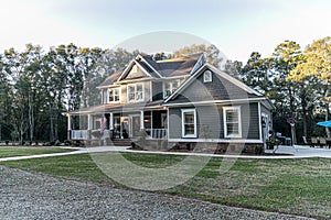 Front view of a large two story blue gray house with wood and vinyl siding