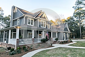 Front view of a large two story blue gray house with wood and vinyl siding