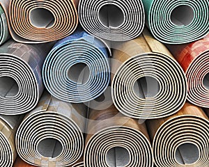 Front view on linoleum rolls with different color, texture, pattern stacked one on another,