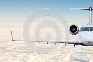 Front view of the luxury business jet flying in the air above the clouds