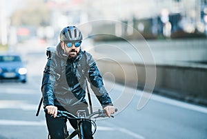 A front view of male bicycle courier delivering packages in city. Copy space.