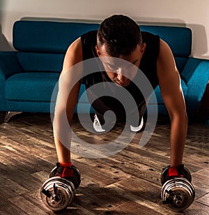 Front view of a man doing plank with dumbbells