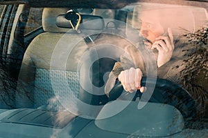 Front view of man driving car and talking on mobile