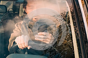 Front view of man driving car and texting on mobile