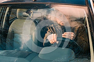 Front view of man driving car and texting on mobile