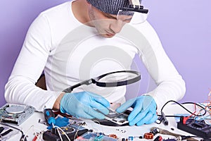 Front view of man showing process of mobile phone repair, radioman using tool equipment to change damaged part of smartphone.