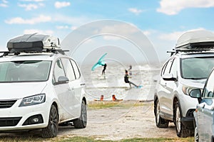 Front view many cars parked with surf board kite equipment on sand beach, van vehicle with rooftop box ocean sea beach