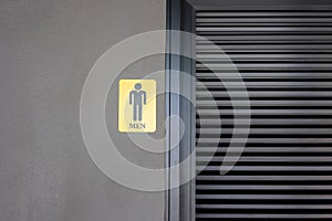 Front view of metallic sign indicating men on dark concrete cement wall shows labelling lavatory or toilet for male which seeing