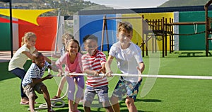 Front view of mixed-race schoolkids playing tug-of-war in the school playground 4k