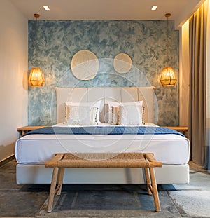 Front view of modern bedroom interior in nautical marine style with blue decorative stucco wall, wicker furniture, wooden ceiling