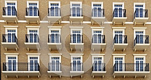 Front view of a modern residential brown brick building with balconies and Windows, close-up, pattern