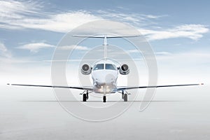 Front view of the modern white private jet isolated on bright background with sky