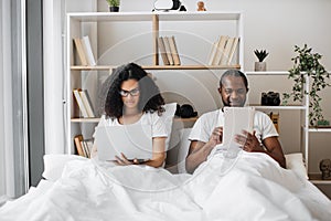 Multicultural couple using gadgets for work at home