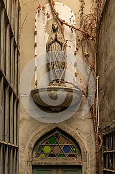 Front view of narrow alley entrance of ancient church with stone woman statue on wooden door