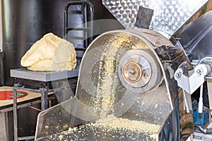 Front view of a nixtamal mill while a man takes out the dough that is being produced photo